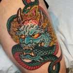 A custom tattoo with foo dog vibes, where the foo dog bites a snake as it wraps around its head, a custom piece by Jacksonville tattoo artist Tim Shafer.