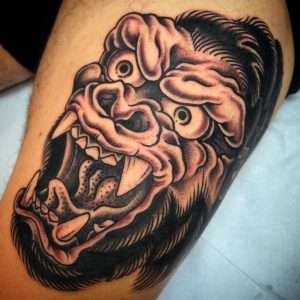 A black and grey traditional gorilla head tattoo above the knee, a custom piece by artist Zach Westcott at Mister Tattoo in Jacksonville, FL.